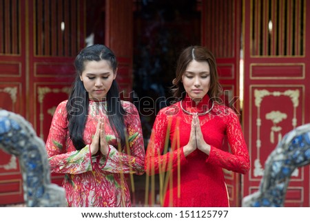 Young charming ladies praying in the Buddhist temple on the foreground