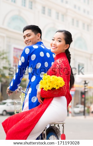 Vietnamese couple in traditional clothes cycling in the city
