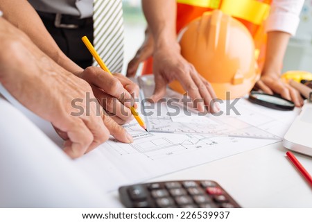 Hands of architects working on blueprints in the office, selective focus