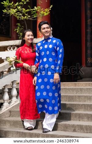 Cheerful young Vietnamese couple in ao dai dresses