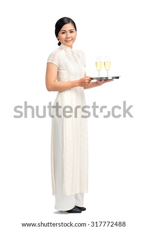 Full-length portrait of Vietnamese waitress carrying tray with champagne glasses