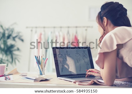 Fashion designer drawing sketches for new collection, rear view