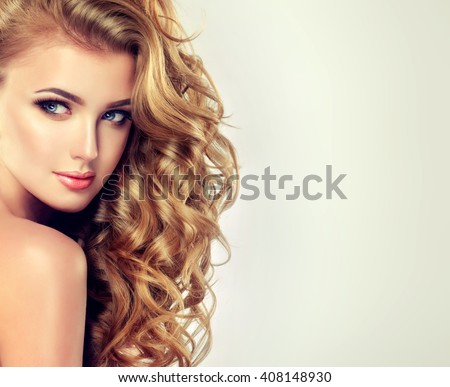 Blondel girl with long wavy hair . Beautiful model with curly hairstyle
