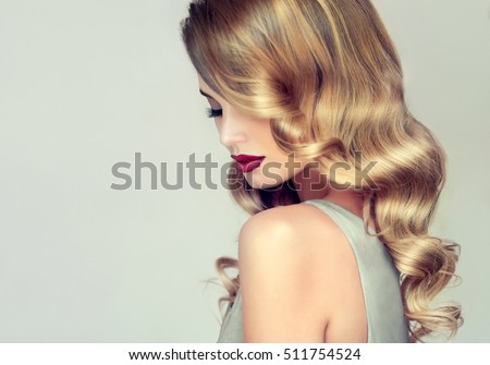 Beautiful girl with long wavy hair . Blonde with curly hairstyle and red lips