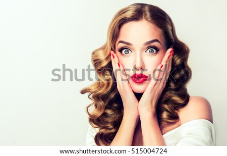 Woman surprise holds cheeks by hand .Beautiful girl with curly hair pointing to looking right . Presenting your product. Isolated on white background. Expressive facial expressions