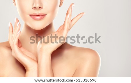 Beautiful Young Woman with Clean Fresh Skin touch own face . Facial treatment . Cosmetology , beauty and spa .