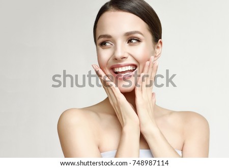 Happy beautiful girl holding her cheeks with a laugh looking to the side. Expressive facial expressions .Cosmetology and Spa