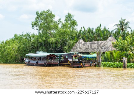 TIEN GIANG, VIETNAM - OCT 5, 2014: Wooden boat on Mekong river in Southern Vietnam. Mekong is the 12th-longest river and flows trough China, Burma, Laos, Thailand, Cambodia, Vietnam