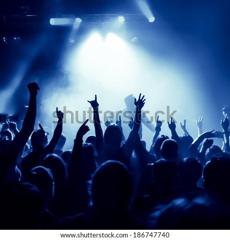 silhouettes of concert crowd in front of bright stage lights, singer on ...
