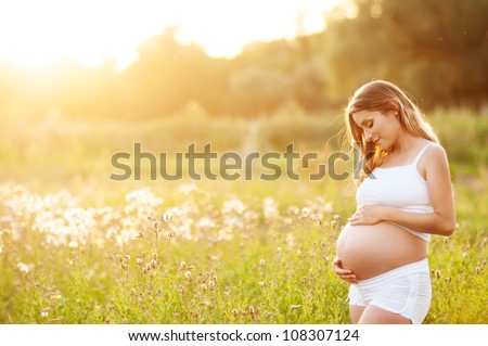 Beautiful pregnant woman relaxing outside in the park