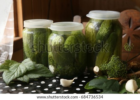 Homemade pickles in glass jars. Pickled cucumbers on table in kitchen. Spices and herbs for making pickles.