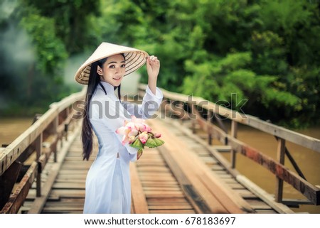 Beautiful Portrait of Asian girls with Ao-Dai Vietnam traditional dress costume woman
,Walk the bridge with Lotus, at VIetnam.