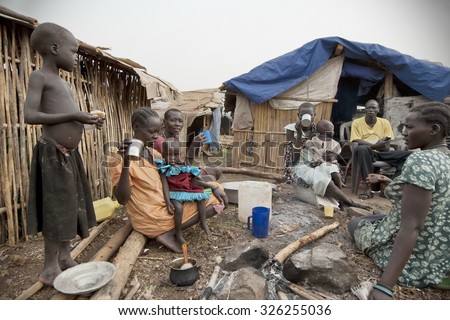JUBA, SUDÃO DO SUL - 28 DE FEVEREIRO: Pessoas não identificadas tomam café da manhã em frente às suas cabanas no campo de deslocados, Juba, Sudão do Sul, 28 de fevereiro de 2012. Eles permanecem em condições adversas por muito tempo.