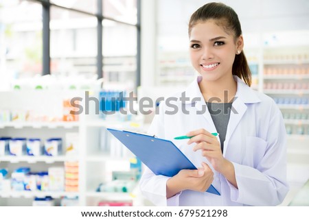 Smiling Asian female pharmacist working in chemist shop or pharmacy