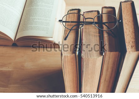 Row of old books with reading glasses above , vintage color tone