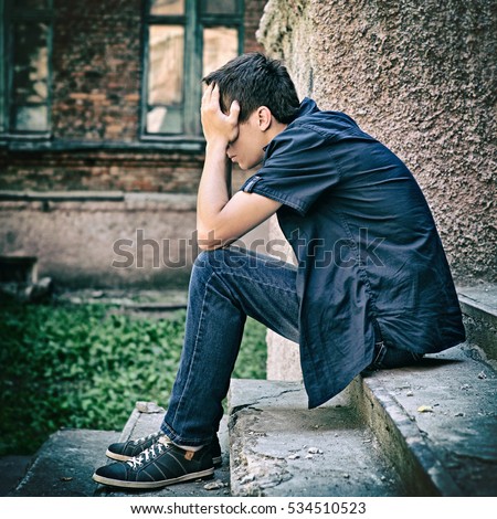 stock-photo-toned-photo-of-sad-teenager-sit-on-the-street-534510523.jpg