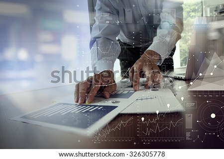 close up of businessman hand working on laptop computer with financial business graph information diagram on wooden desk as concept
