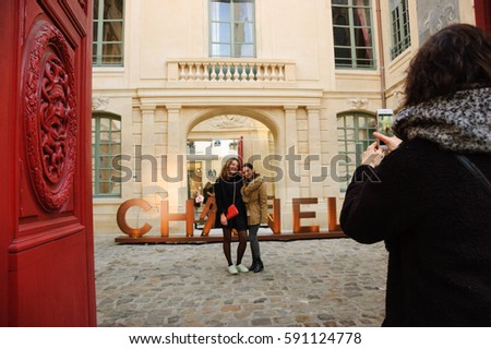 PARIS, FRANCE - JANUARY 28, 2017: Chanel shop in old Marais quarter. Chanel fashion house founded by Coco Chanel is symbol of haute couture and luxury goods. Young girls take photo with brand sign.