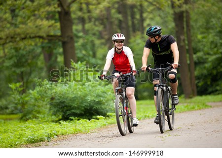 happy Man and woman exercising with bicycles outdoors, they are a couple in park