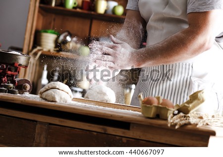 Male baker prepares bread. Male baker slaps on dough. Making bread.