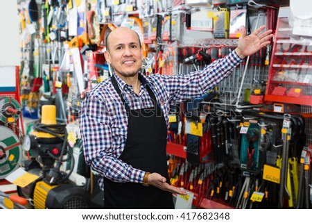 Smiling salesman showing different tools and instruments in wholesale