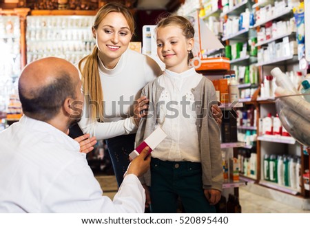 Elderly positive male pharmacist in white coat working the pharmaceutical store and consulting customers