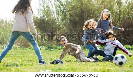 Group of children running after ball in spring park