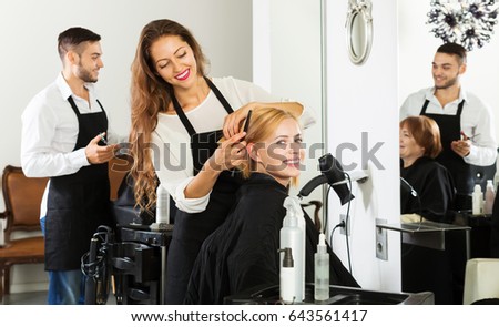 Hairstylist cuts young woman's hair in the barbershop