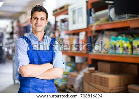Portrait of cheerful working man in uniform on his workplace in building store.