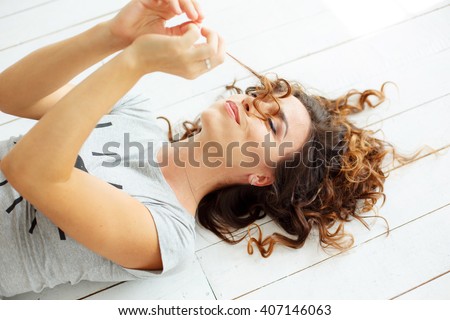 Beautiful curly-haired girl lying on the floor and touching her hair. beautiful girl posing on camera. Happy smiling model