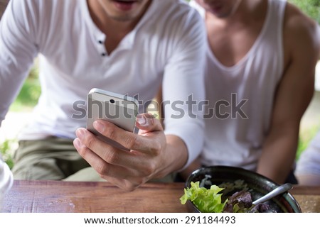man using app a smartphone playing social network Happy gay couple man using app a smartphone playing social network Happy gay couple