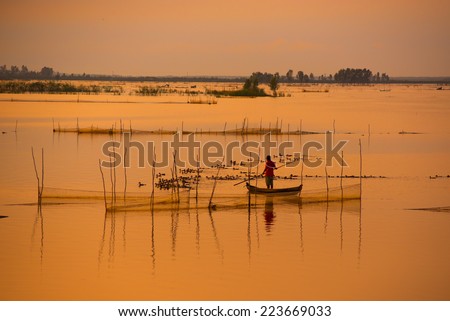 Fisher on boat in water season in sunrise in Dong Thap, Vietnam