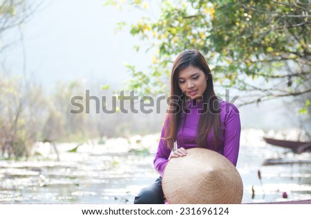 Vietnamese girl with traditional dress (ao dai) and conical hat in Yen stream in Hanoi, Vietnam