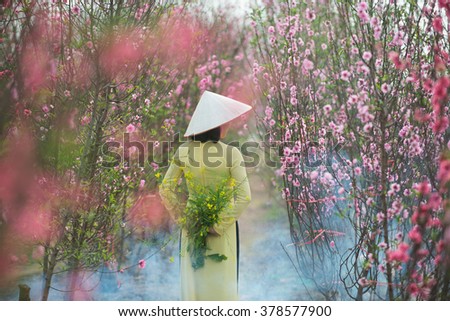 Beautiful Vietnamese girls with traditional dress (ao dai) is in peach flower garden in Hanoi, Vietnam
