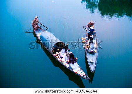HUE, VIETNAM, APRIL 17, 2016: Vietnamese girls with Ao Dai are lighting candle in lantern to pray in the river. Ao dai is famous traditional custume for woman in VIetnam.