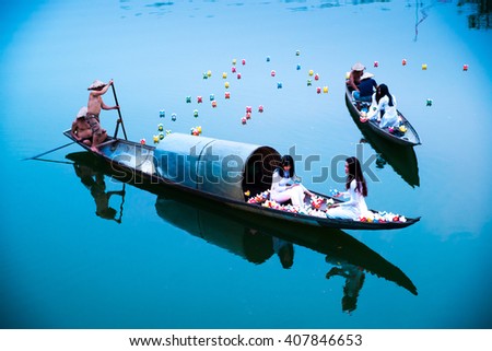 HUE, VIETNAM, APRIL 17, 2016: Vietnamese girls with Ao Dai are lighting candle in lantern to pray in the river. Ao dai is famous traditional custume for woman in VIetnam.