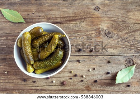 Pickles. Bowl of pickled gherkins (cucumbers) over rustic wooden background with copy space.