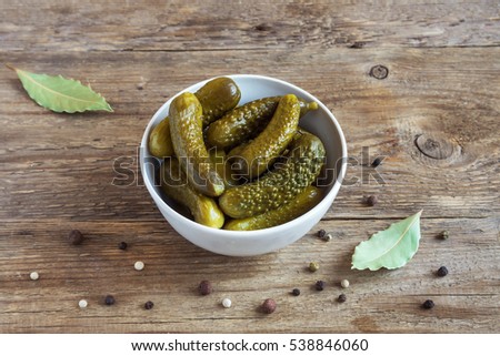 Pickles. Bowl of pickled gherkins (cucumbers) over rustic wooden background close up.