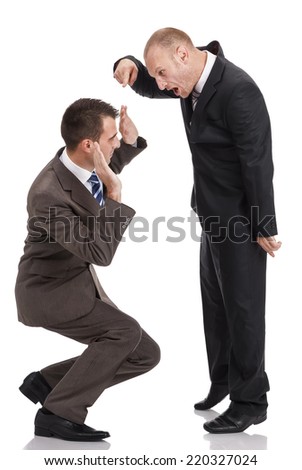 Angry employer in a dark suit shouting at a crouched employee in a ...