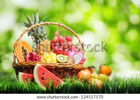 Basket of tropical fruits on green grass.