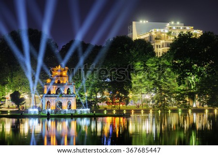 Night view of the Hoan Kiem Lake (Lake of the Returned Sword) and the Turtle Tower among blue light rays at historic centre of Hanoi in Vietnam. The Hoan Kiem Lake is a popular tourist destination.