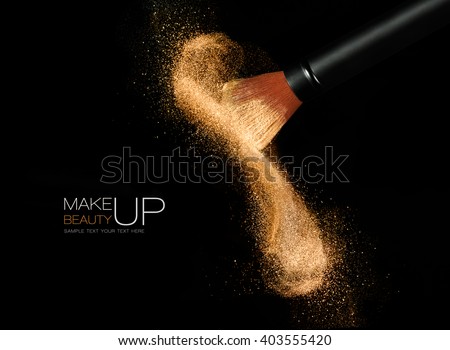 Soft cosmetics brush releasing a cloud of glowing sparkling face powder over a black background with copy space in a beauty and makeup concept