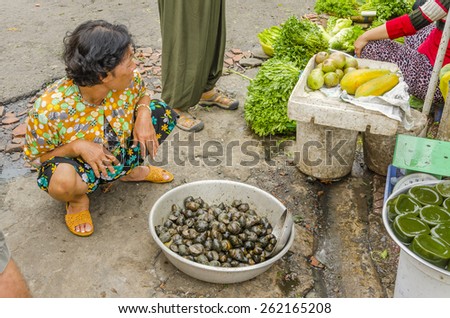 VINH LONG, VIETNAM, JANUARY 3, 2013: Local woman sells snails on the street in Vinh Long market
