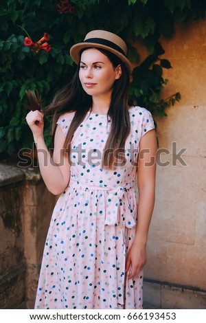 https://thumb1.shutterstock.com/display_pic_with_logo/1357633/666193453/stock-photo-young-beautiful-woman-in-long-dress-with-colored-polka-dots-and-stylish-hat-enjoys-good-weather-in-666193453.jpg
