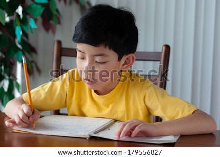 An Asian boy doing his homework at home.