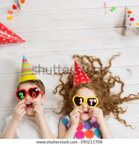 New Years 2017 party. Funny children hold 2017 shaped candles lies on the wooden floor. High top view.