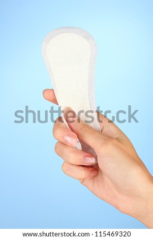 woman's hand holding a daily sanitary pad on blue background close-up ...