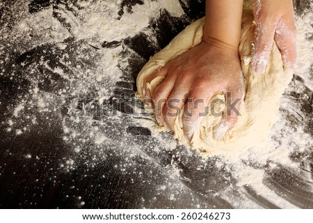 Making dough by female hands on wooden table background