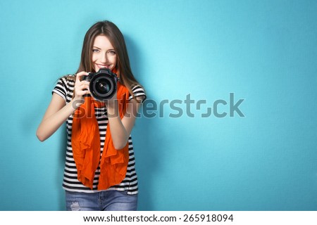 Young female photographer taking photos on blue background