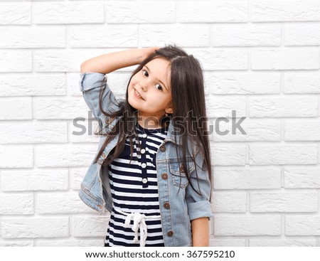 Little girl on a white brick wall background